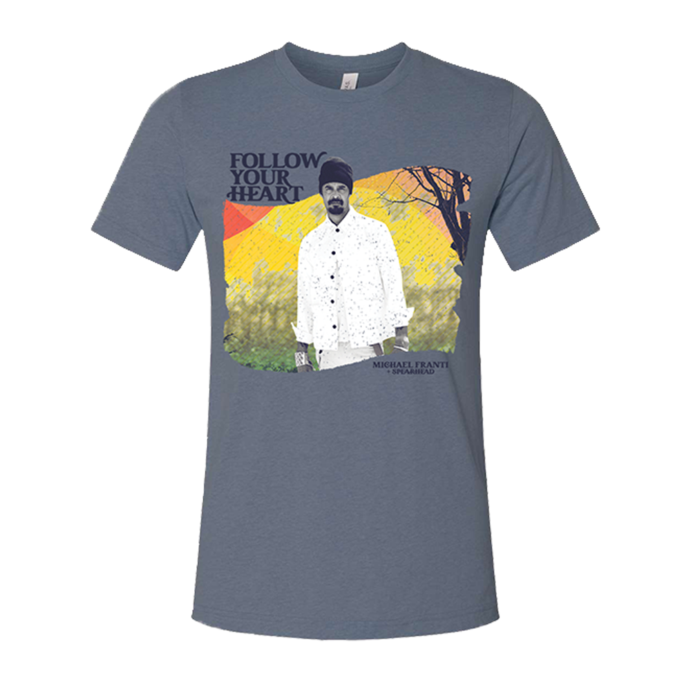 Gray t-shirt with a colorful graphic design featuring a man in a white shirt and the text ’FOLLOW YOUR HEART’.