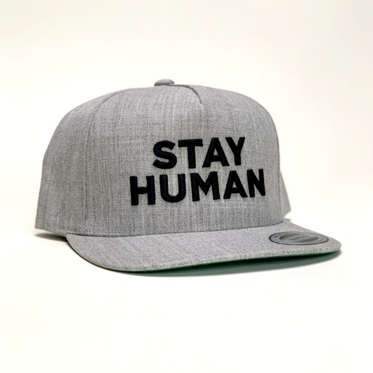 Gray baseball cap with ’STAY HUMAN’ embroidered in black letters on the front.